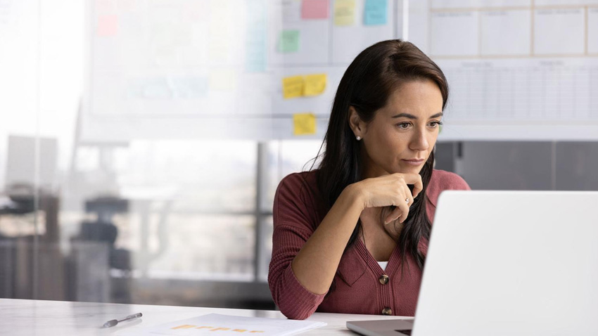 Woman sitting at a desk looking at a laptop